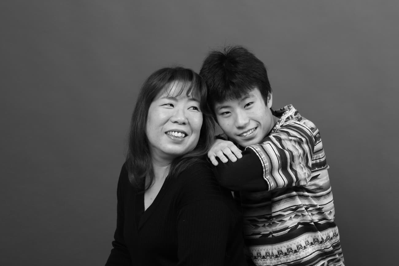 自閉症の男子と肩を組む母親