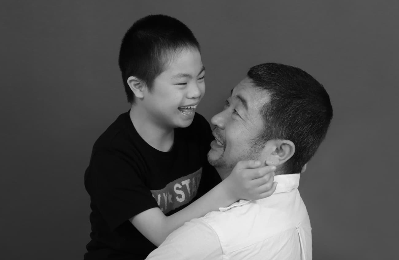 ダウン症の男の子を抱っこする父