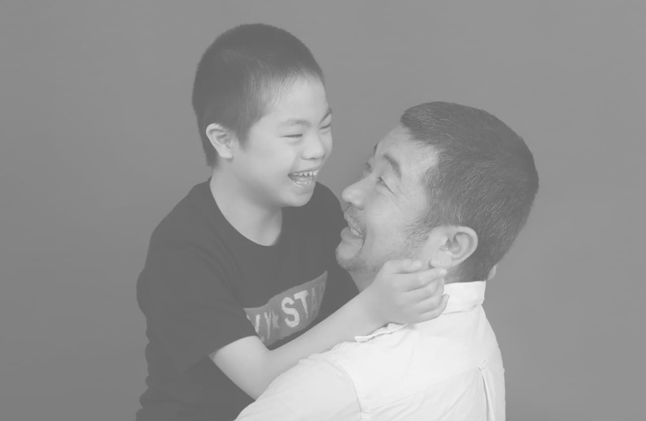 ダウン症の男の子を抱っこする父