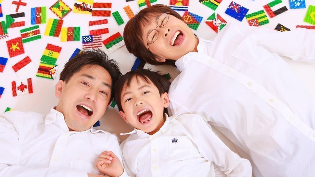 世界の国旗に囲まれて寝転び笑う家族